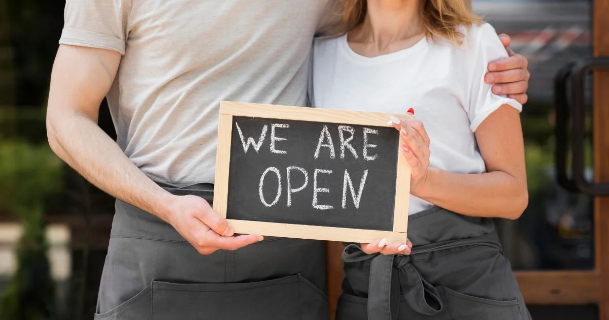 Small business owners holding we are open sign