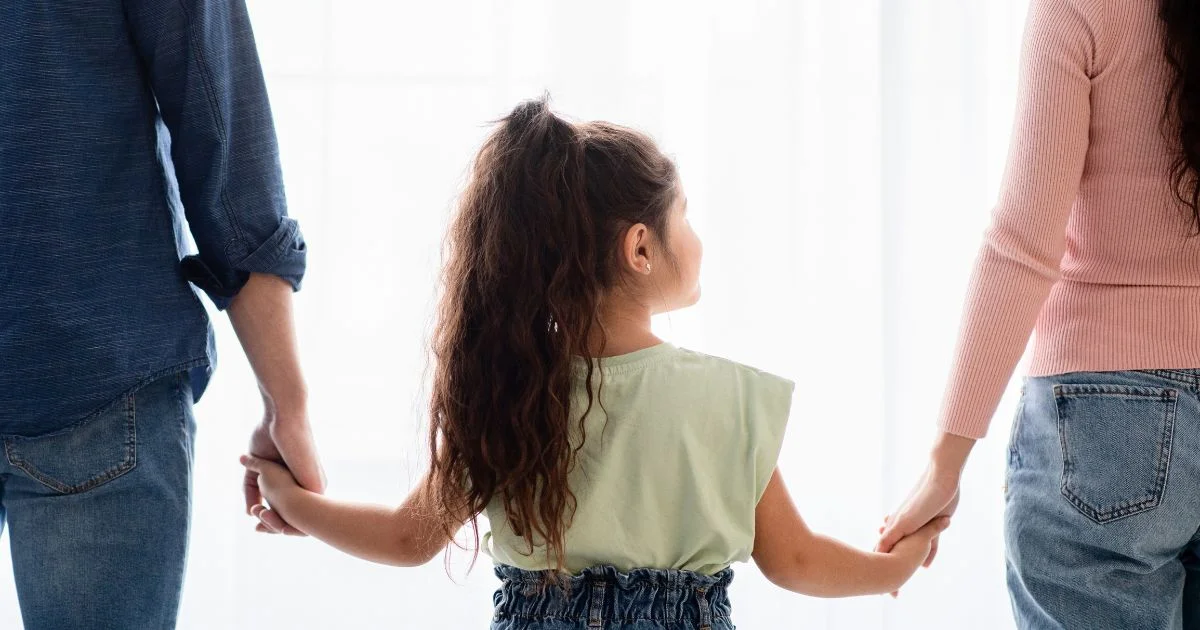 Child holding hands with separated parents
