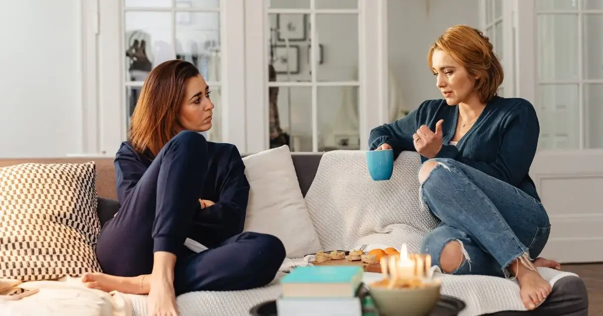 Two women discussing personal matters on a couch