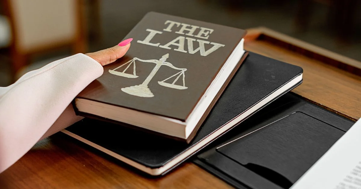 Law book resting beside laptop on desk.